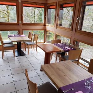 a restaurant with wooden tables and chairs and windows at Auberge Le Moulin Du Plain in Goumois