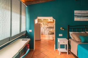 a bedroom with green walls and a bed and a kitchen at Ciauru ri Casa in Mascalucia