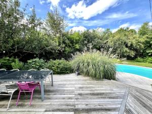 a wooden deck with a table and chairs next to a pool at Villa piscine privée 8-10 pers Strasbourg 10 min in Mundolsheim