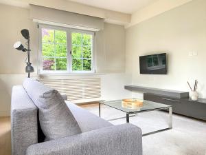 a living room with a couch and a tv at Villa piscine privée 8-10 pers Strasbourg 10 min in Mundolsheim