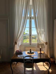 a table with a lamp in front of a window at Château de Ternay in Ternay