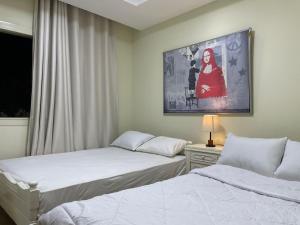 a bedroom with two beds and a painting on the wall at Modern apartment with garden in Sheikh Zayed