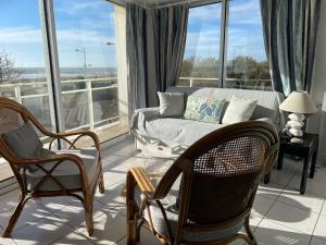 a living room with a couch and chairs and a window at Appartement T2 vue mer les pieds dans l'eau avec parking privé in Saint-Jean-de-Monts