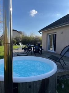 einen Whirlpool auf einer Terrasse mit einem Tisch und Stühlen in der Unterkunft House with Outdoor Jacuzzi in Rocroi
