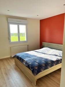 a bedroom with a bed with a red wall and a window at House with Outdoor Jacuzzi in Rocroi