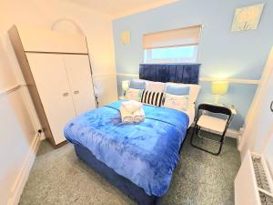 ein Schlafzimmer mit einem blauen Bett und einem Stuhl in der Unterkunft Gillings Villa -5 Bed Great For Long & Short Stay!!! Gillingham Kent in Hoo