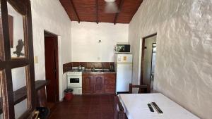 a kitchen with a stove and a white refrigerator at EL PASO IBERA, cabañas equipadasy piscina in Colonia Carlos Pellegrini