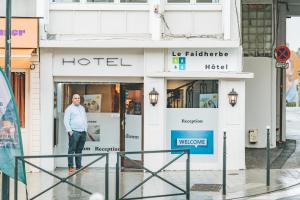 a man standing in front of a hotel at Le Faidherbe Hotel Coeur de ville in Boulogne-sur-Mer