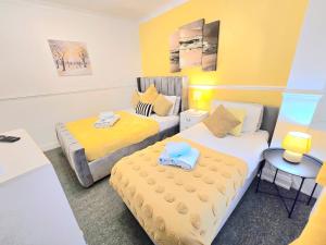 2 Betten in einem kleinen Zimmer mit gelben Wänden in der Unterkunft Gillings Villa -5 Bed Great For Long & Short Stay!!! Gillingham Kent in Hoo + 14 Fotos
