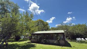 a small shack in a field with chairs and trees at EL PASO IBERA, cabañas equipadasy piscina in Colonia Carlos Pellegrini