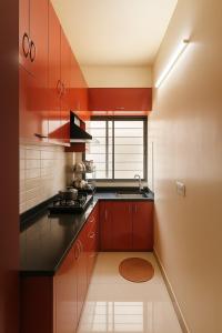a kitchen with red cabinets and a sink at Fully furnished 2 BHK Flat in kolkata