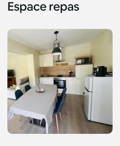 a room with a table and a kitchen with a white refrigerator at Maisonnette tout confort in Villette-dʼAnthon