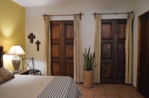 ein Schlafzimmer mit einem Bett, Holztüren und einem Kreuz in der Unterkunft en corazón centro Histórico, in Morelia