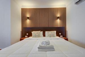 a bedroom with a large white bed with towels on it at Tritoni Alta suites in Il-Gżira