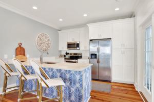 una cocina con armarios blancos y una isla de cocina con sillas en Cherokee Rose, en Tybee Island
