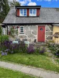 ein Steinhaus mit einer roten Tür und einigen Blumen in der Unterkunft Eternellgården, Stenshuvudsvägen , Kivik in Kivik