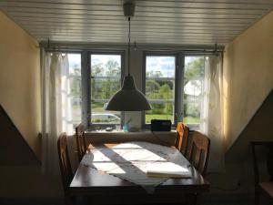 ein Esstisch mit Stühlen und einer Lampe sowie Fenster in der Unterkunft Eternellgården, Stenshuvudsvägen , Kivik in Kivik