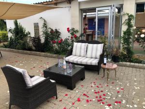 eine Terrasse mit 2 Stühlen und einem Tisch mit Blumen in der Unterkunft Good Times Cafe in Teyateyaneng