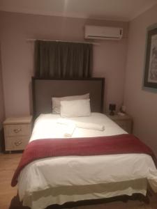 ein Schlafzimmer mit einem großen weißen Bett mit einer roten Decke in der Unterkunft Good Times Cafe in Teyateyaneng