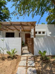 Casa blanca con puerta de madera y valla en Casa Mon Repos en Careyes, en Careyes