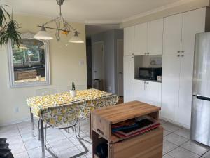 eine Küche mit Tisch und eine Küche mit weißen Schränken in der Unterkunft Escapade familiale à Longueuil in Longueuil