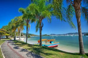 ein Boot, das an einem Strand neben Palmen geparkt ist in der Unterkunft Casa no centro da cidade a 600 metros da praia. in Porto Belo