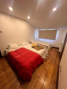 a bedroom with a large bed with a red blanket at Casona IslaNegra in Isla Negra