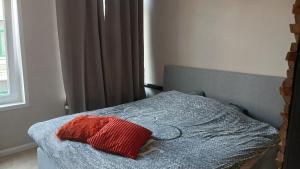 a bedroom with a bed with a red pillow on it at La Nonne Blanche in Ostend