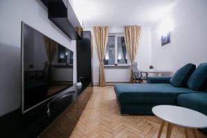 ein Wohnzimmer mit einer blauen Couch und einem Fernseher in der Unterkunft Cozy central apartament in Craiova