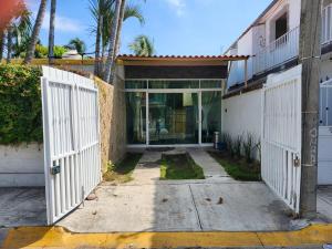 a house with a white gate and a building at Casa Elbatros in Manzanillo