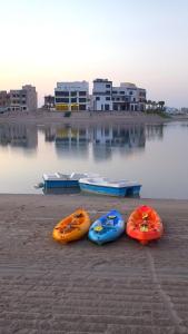 four kayaks are lined up next to the water at Shaleeh 285 شاليه العائلة in Al Khīrān