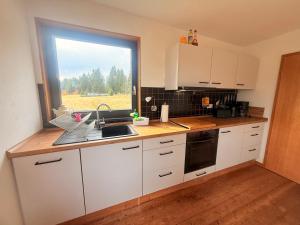 une cuisine avec des placards blancs et une grande fenêtre dans l'établissement Tiny Chalet Stuga Am Rennsteig mit Kamin und Garten, Hunde Willkommen, à Eisfeld 7 autres photos