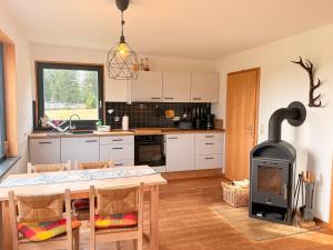 - une cuisine avec une table et un poêle à bois dans l'établissement Tiny Chalet Stuga Am Rennsteig mit Kamin und Garten, Hunde Willkommen, à Eisfeld