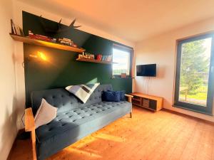 un salon avec un canapé bleu et une fenêtre dans l'établissement Tiny Chalet Stuga Am Rennsteig mit Kamin und Garten, Hunde Willkommen, à Eisfeld