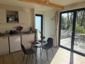 a kitchen and dining room with a table and chairs at Studio neuf dans un espace boisé in Locronan