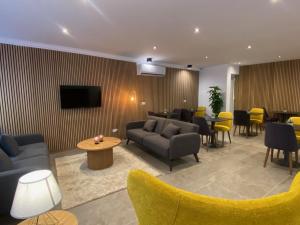 a lobby with couches and a tv and tables and chairs at Tritoni Alta suites in Il-Gżira