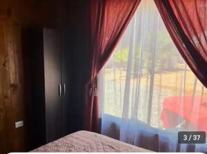 Un dormitorio con una gran ventana con cortinas rojas. en Refugio Vilches, en Vilches 5 fotos más