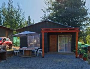 un patio con una mesa y una sombrilla en Refugio Vilches, en Vilches