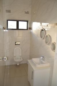 a white bathroom with a toilet and a sink at Woodmead Meadows in Harare +24 photos