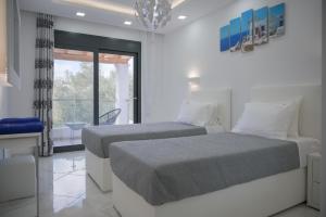 zwei Betten in einem weißen Zimmer mit Fenster in der Unterkunft Diamond Luxury Villa Corfu in Káto Spílaion + 37 Fotos