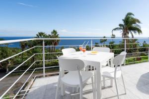 ein weißer Tisch und Stühle auf einem Balkon mit Blick auf das Meer in der Unterkunft GiuMar Apartments Aci Trezza in Aci Catena + 9 Fotos