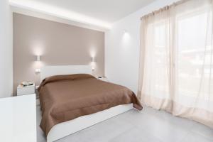 ein weißes Schlafzimmer mit einem Bett und einem großen Fenster in der Unterkunft GiuMar Apartments Aci Trezza in Aci Catena