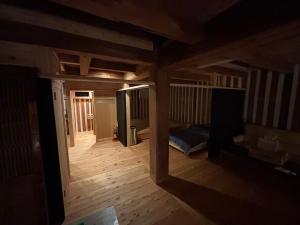 an empty room with a bed and wooden floors at 離れの宿 かぶろの庭 in Matsukawa