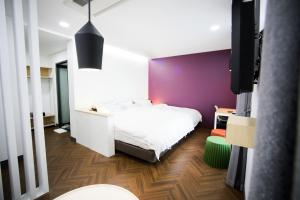 a bedroom with a white bed and a purple wall at Boutique Hotel Wine in Gwangju