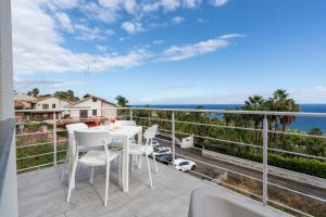 ein weißer Tisch und Stühle auf einem Balkon mit Blick auf das Meer in der Unterkunft GiuMar Apartments Aci Trezza in Aci Catena
