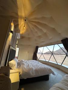 a bedroom with a bed and a large window at SELEN RUM LUXURY CAMP & Jeep Tours in Wadi Rum