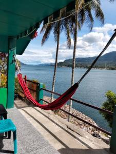 a hammock hanging from a building with a view of the water at Mario Lakeside Apartments in Tuk Tuk