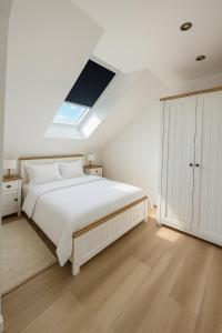 a white bedroom with a white bed and a skylight at Twenty2 Apartments in Brühl