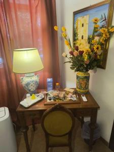 a table with a lamp and a vase with flowers on it at L'Antica Quercia B&B in CastellʼUmberto