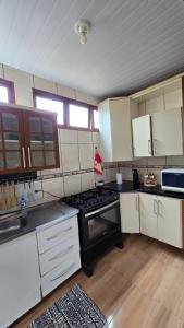a large kitchen with a stove and white cabinets at Casa com Piscina Peró in Cabo Frio